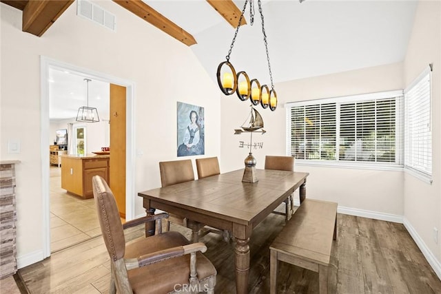 dining room featuring a chandelier, vaulted ceiling with beams, and light hardwood / wood-style floors