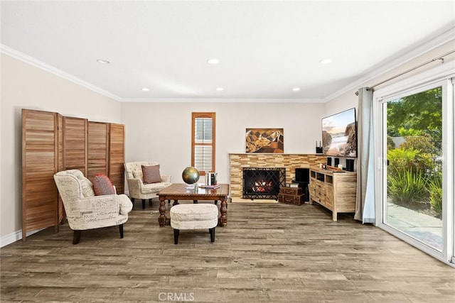 sitting room featuring hardwood / wood-style floors, a stone fireplace, and crown molding