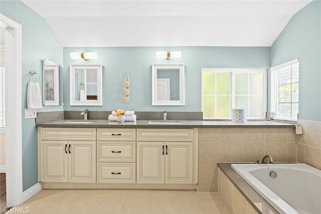 bathroom with tile patterned flooring, vanity, a relaxing tiled tub, and lofted ceiling