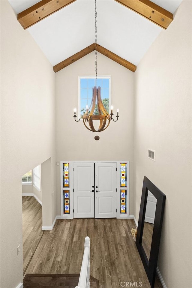 foyer entrance with high vaulted ceiling, a healthy amount of sunlight, and wood-type flooring