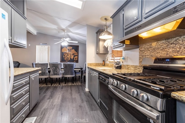 kitchen featuring lofted ceiling with beams, sink, stainless steel range with gas stovetop, decorative light fixtures, and dark hardwood / wood-style flooring