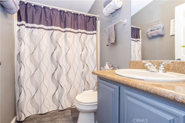 bathroom with vaulted ceiling, hardwood / wood-style flooring, vanity, and toilet