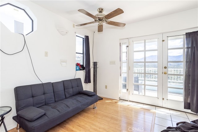 living room featuring light wood-type flooring, a mountain view, ceiling fan, and french doors