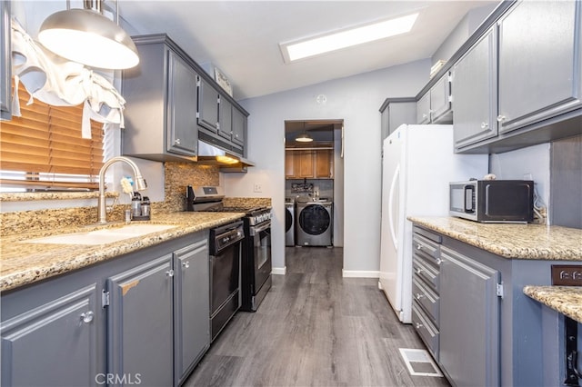 kitchen with sink, lofted ceiling, hanging light fixtures, stainless steel appliances, and independent washer and dryer