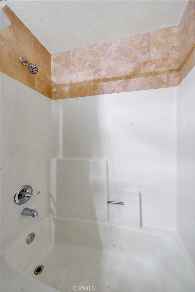 bathroom with a textured ceiling and shower / washtub combination