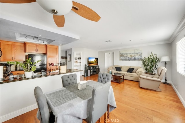 dining area featuring crown molding, ceiling fan, light hardwood / wood-style flooring, and track lighting