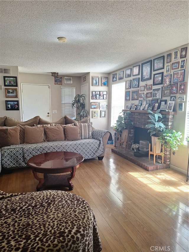 living room featuring a brick fireplace, hardwood / wood-style flooring, and a textured ceiling