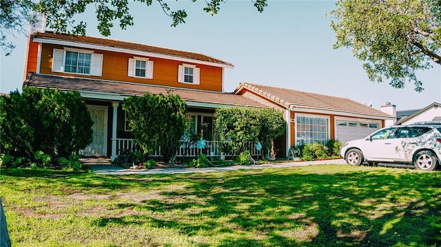 view of front of property featuring a chimney, a porch, an attached garage, and a front yard