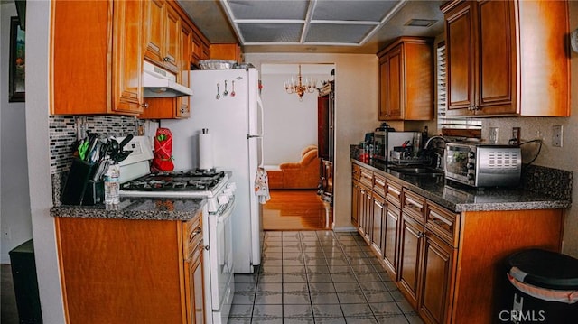 kitchen featuring brown cabinets, white gas range oven, under cabinet range hood, and a sink