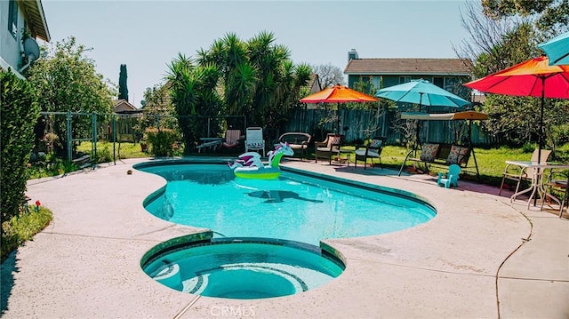 view of swimming pool featuring a patio, fence, and a pool with connected hot tub