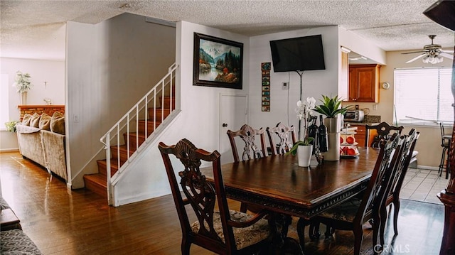 dining area featuring a textured ceiling, wood finished floors, and stairs