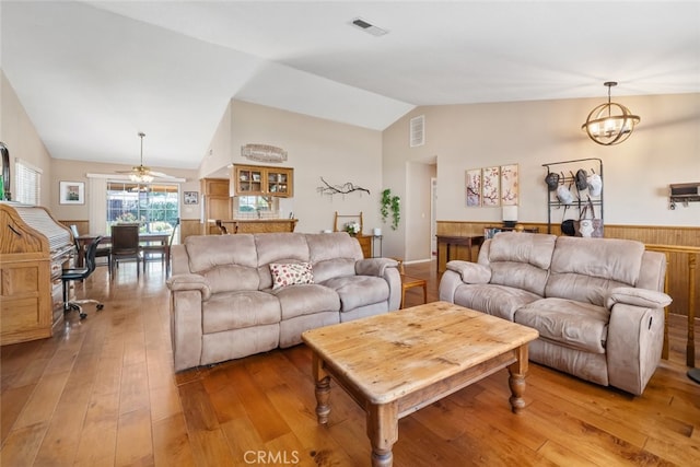 living room featuring ceiling fan with notable chandelier, lofted ceiling, and light wood-type flooring