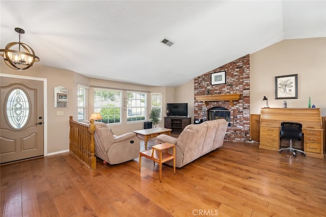 living room featuring a brick fireplace, light hardwood / wood-style flooring, a chandelier, and lofted ceiling