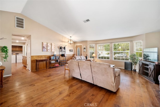 living room with lofted ceiling, independent washer and dryer, and hardwood / wood-style floors