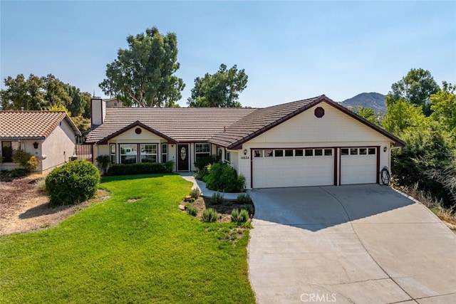 single story home with a mountain view, a front lawn, and a garage