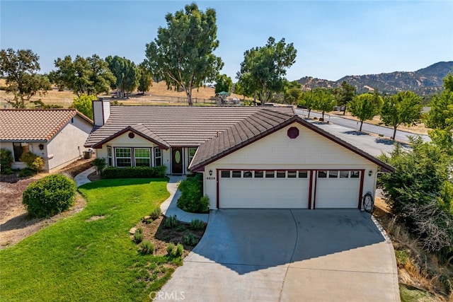 ranch-style home featuring a garage, a mountain view, and a front yard