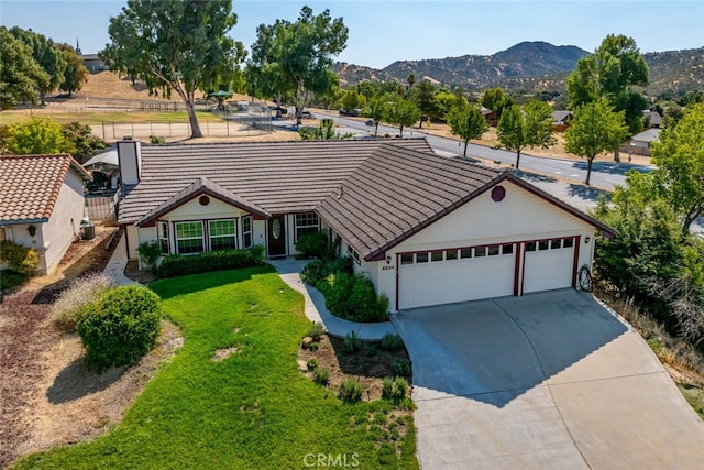 single story home featuring a mountain view, a front lawn, and a garage