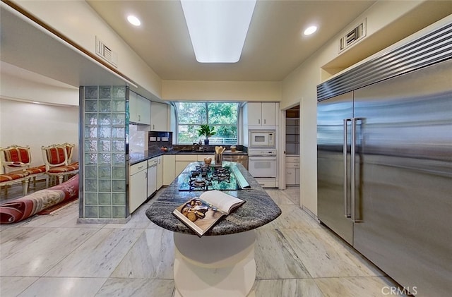 kitchen featuring built in appliances, sink, and white cabinetry