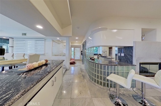 kitchen with white microwave, dark stone countertops, and white cabinets