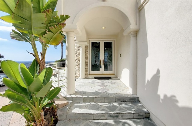 view of exterior entry featuring french doors and a water view