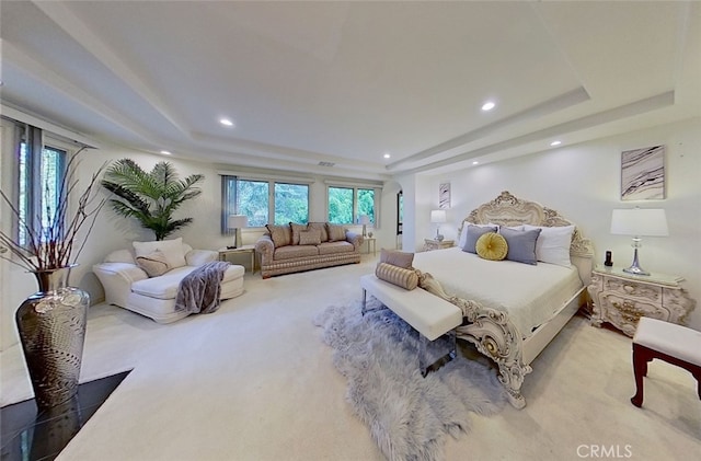 carpeted bedroom with a tray ceiling and multiple windows