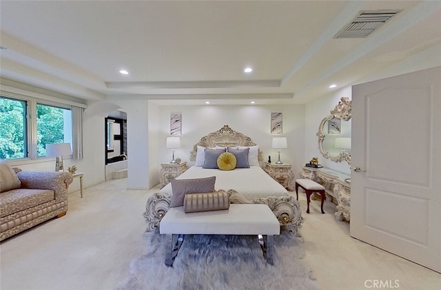 bedroom featuring a tray ceiling and light carpet