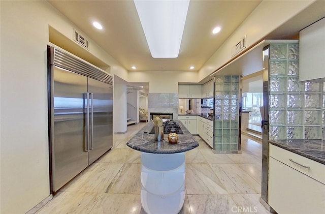 kitchen with built in refrigerator, black gas stovetop, a center island, and decorative backsplash