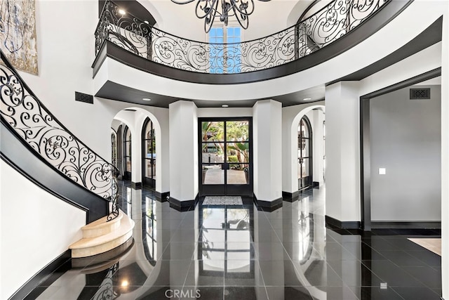 foyer entrance with an inviting chandelier, a high ceiling, and french doors