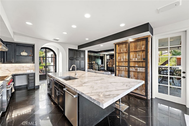 kitchen with backsplash, light stone counters, sink, a breakfast bar area, and a large island