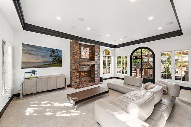 carpeted living room featuring a fireplace, a raised ceiling, and crown molding