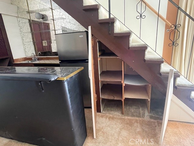 interior space featuring stainless steel refrigerator, light colored carpet, and white cabinets