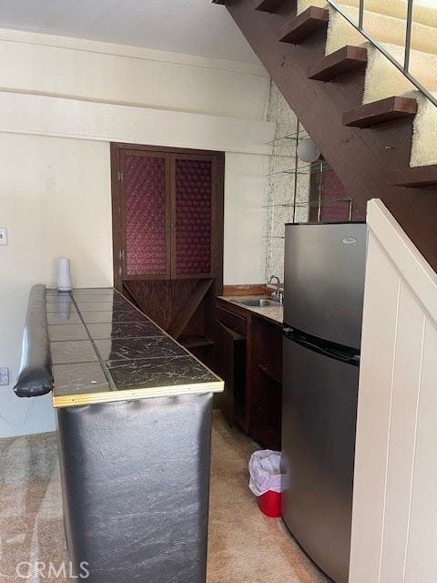 kitchen with ornamental molding, sink, carpet floors, and stainless steel refrigerator