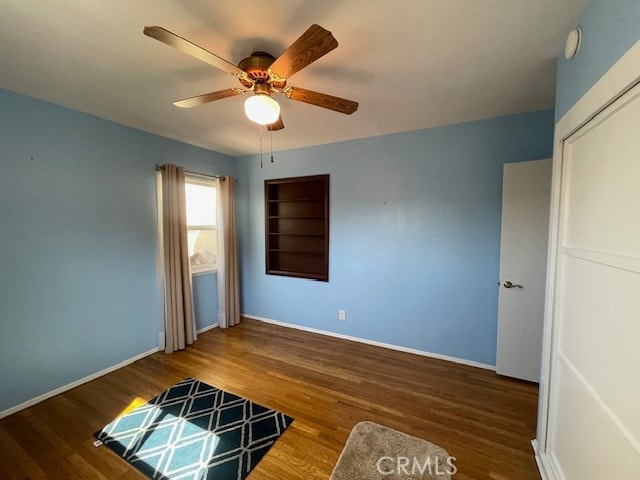 unfurnished bedroom featuring dark wood-type flooring, ceiling fan, and a closet