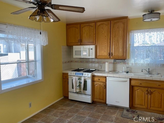 kitchen featuring decorative backsplash, white appliances, tile countertops, and plenty of natural light