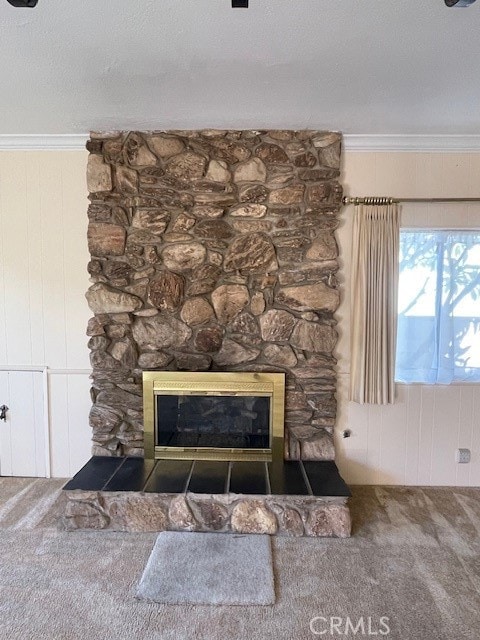 interior details featuring a stone fireplace, a textured ceiling, crown molding, carpet, and wooden walls