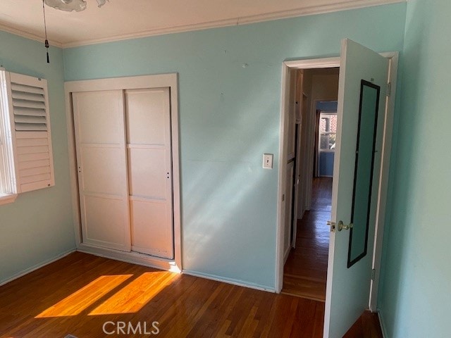 unfurnished bedroom featuring crown molding, hardwood / wood-style floors, and a closet