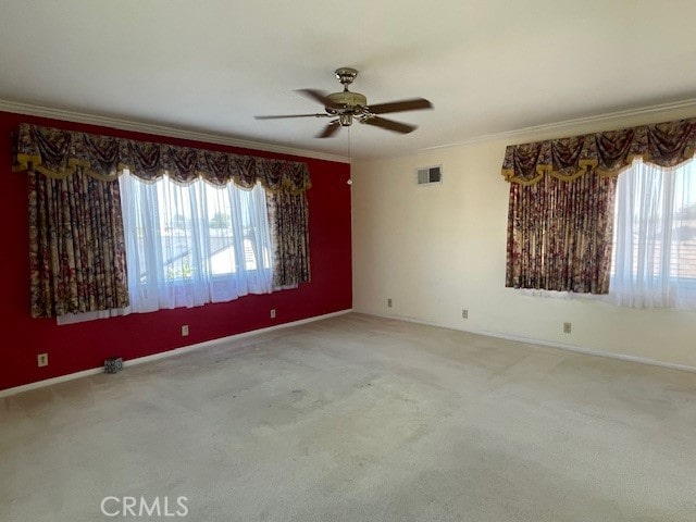 empty room with ceiling fan, ornamental molding, carpet flooring, and a wealth of natural light