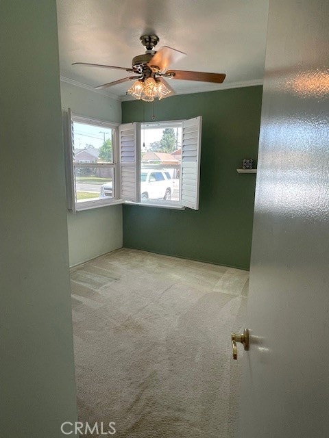 unfurnished room with carpet flooring, ornamental molding, and ceiling fan