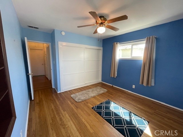 unfurnished bedroom featuring a closet, hardwood / wood-style flooring, and ceiling fan