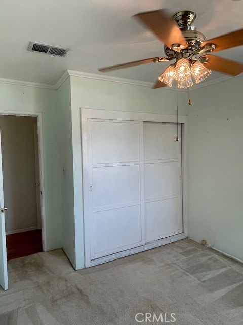 unfurnished bedroom with ornamental molding, a closet, and ceiling fan