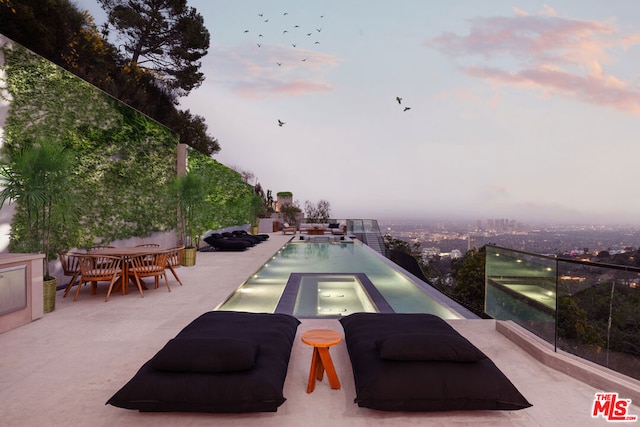 patio terrace at dusk with a swimming pool with hot tub