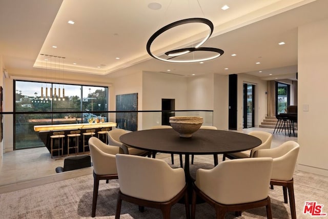 dining area with a raised ceiling and indoor bar