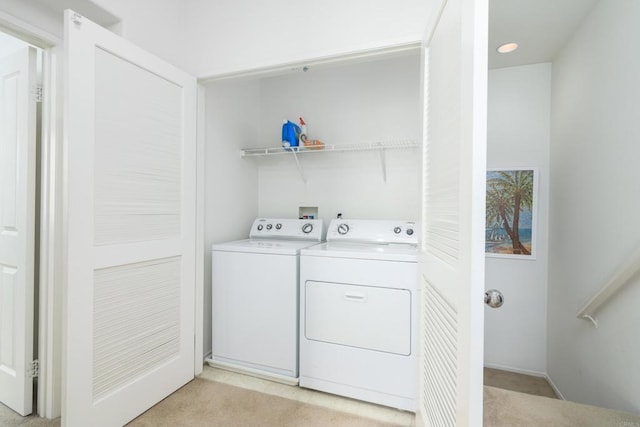 clothes washing area with washer and clothes dryer and light colored carpet