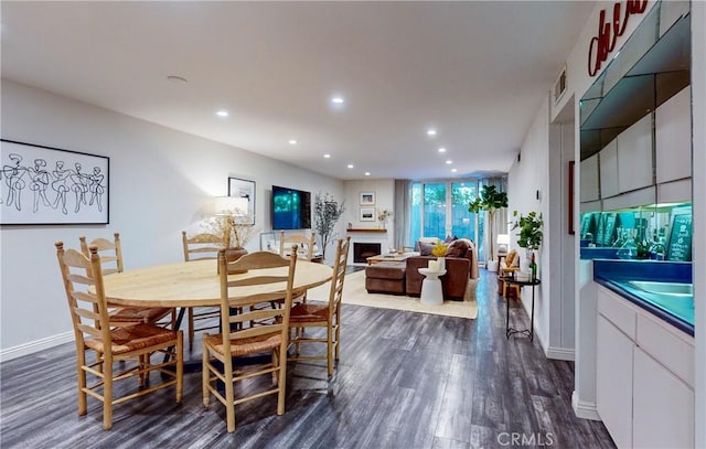 dining room with dark wood-style floors, a fireplace, baseboards, and recessed lighting