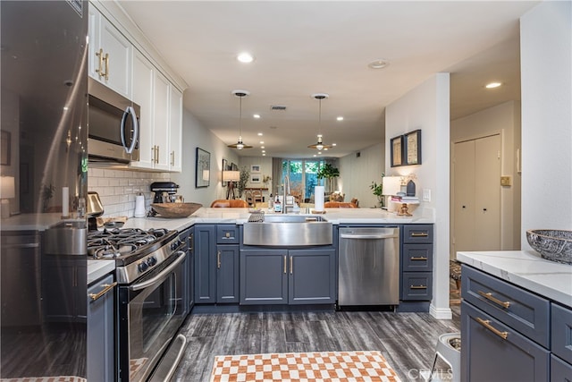 kitchen with sink, white cabinetry, kitchen peninsula, stainless steel appliances, and dark hardwood / wood-style flooring