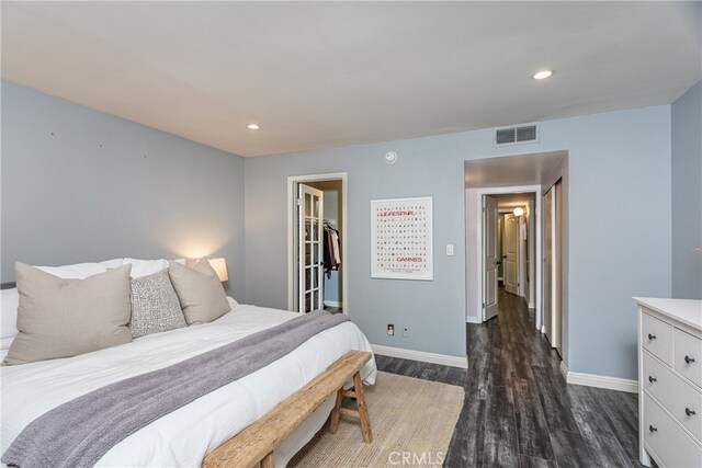 bedroom with a closet, a walk in closet, and dark wood-type flooring