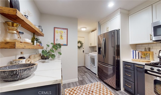 kitchen featuring white cabinets, tasteful backsplash, dark wood-type flooring, stainless steel appliances, and independent washer and dryer