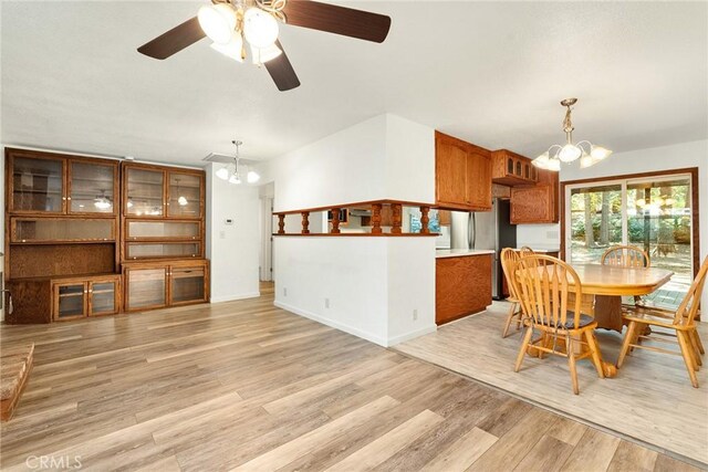 dining space with light wood-style floors, ceiling fan with notable chandelier, and baseboards