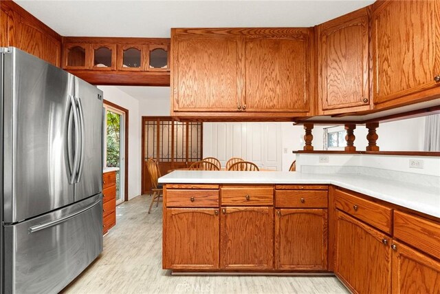 kitchen featuring light countertops, light wood-style flooring, brown cabinets, and freestanding refrigerator