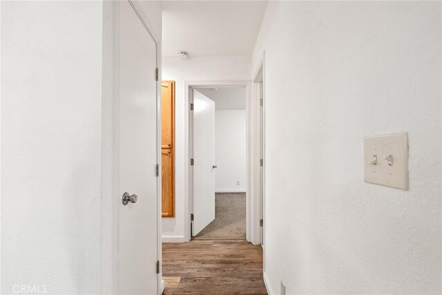 corridor with baseboards and wood finished floors
